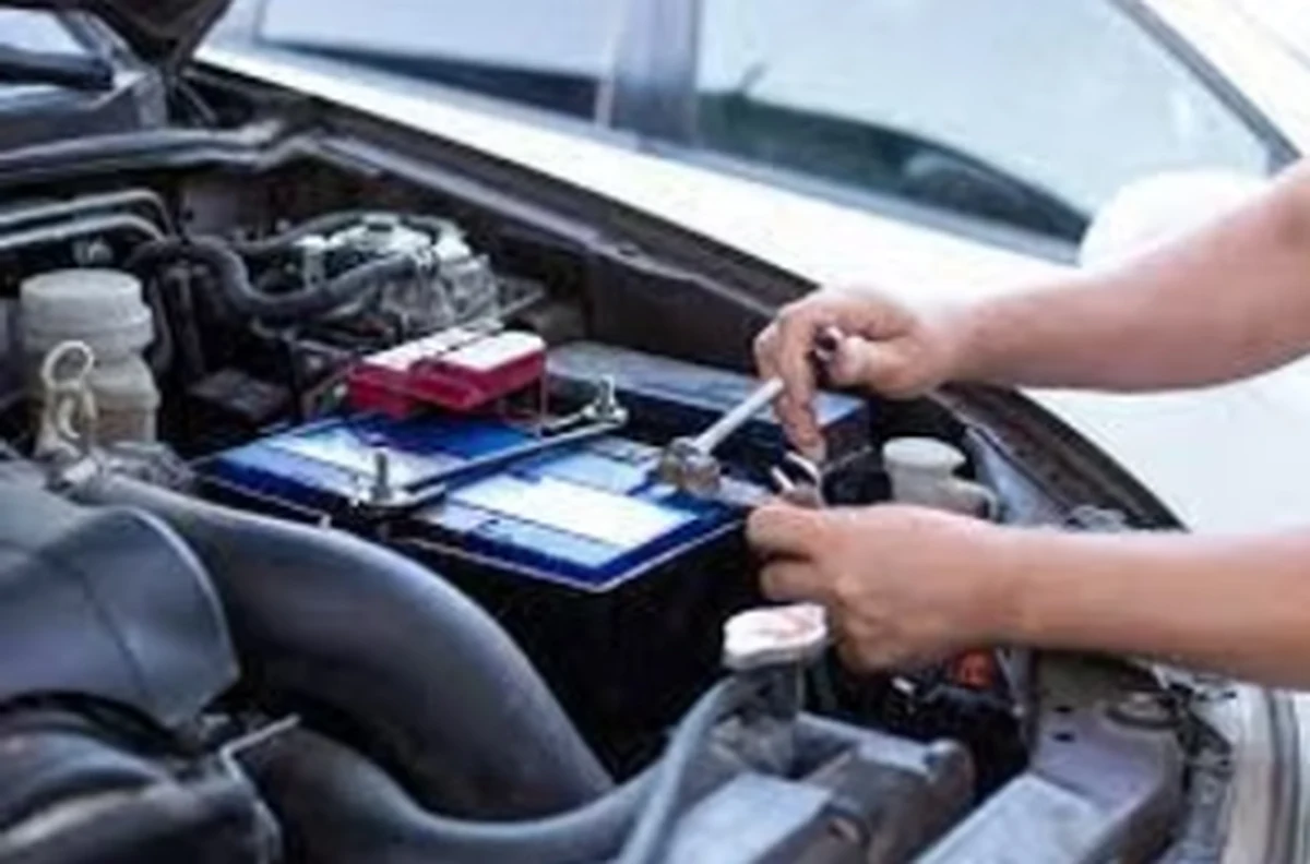 Mobile mechanic replacing a car battery under the bonnet